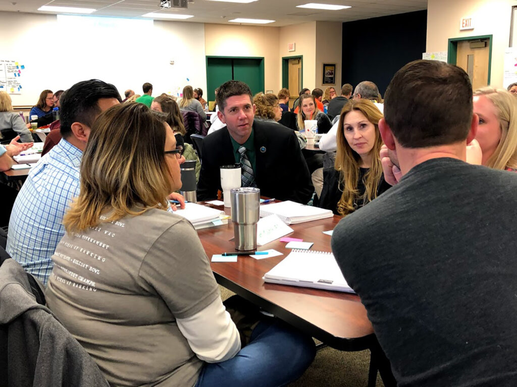 Brig Leane, sitting at a table and training five other people at a school in Wyoming